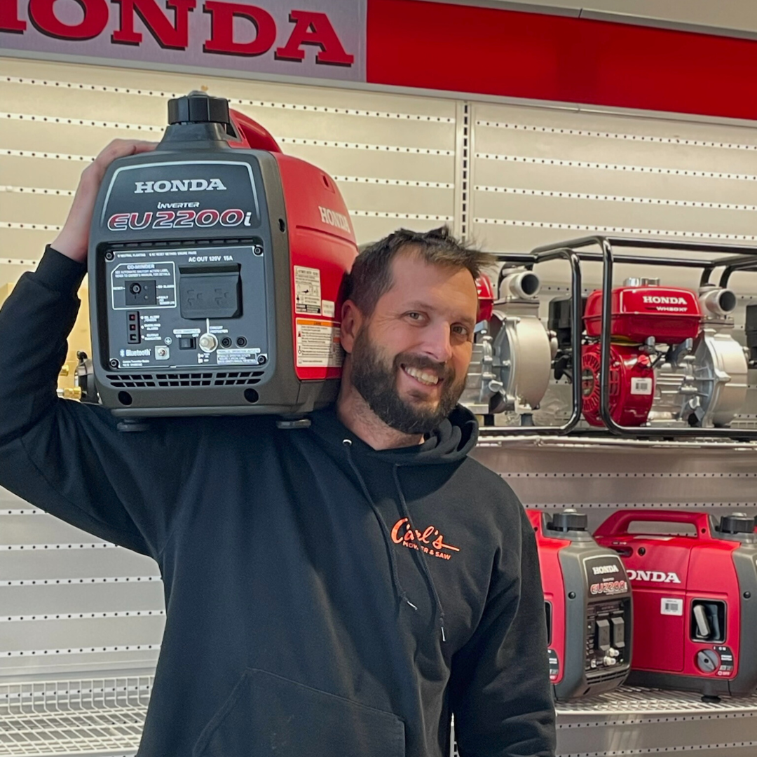 Clayton smiling and holding a Honda EU2200i generator on his shoulder