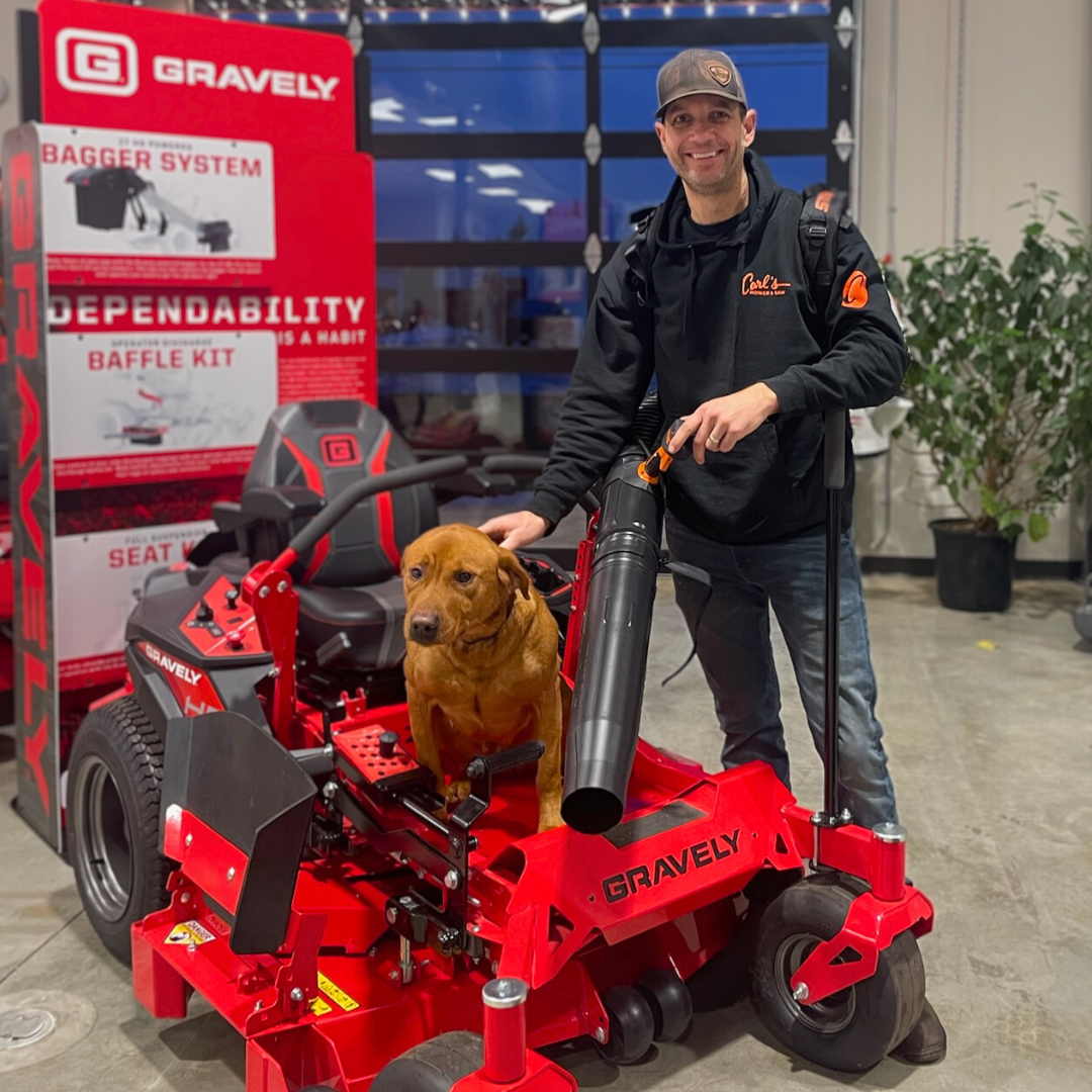 Carl G. smiling with a STIHL BR 600 backpack blower on his back standing next to a Gravely ZT HD lawn mower with his dog sitting on it