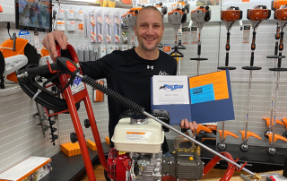 Man holding up owner's manual for new power washer that is on a table